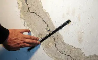 A wall with a large crack is being inspected by a professional in Chula Vista, CA